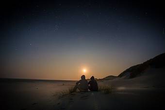 Un couple assis côte à côte regarde le soleil se coucher