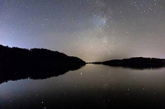 Die Milchstraße über einem Fjord bei Nacht
