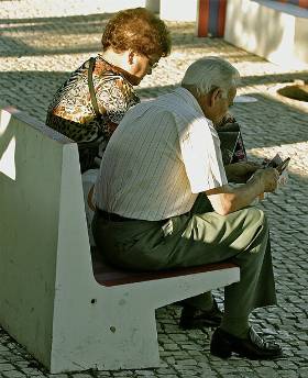 Ein älteres Paar sitzt auf einer Bank und liest gemeinsam